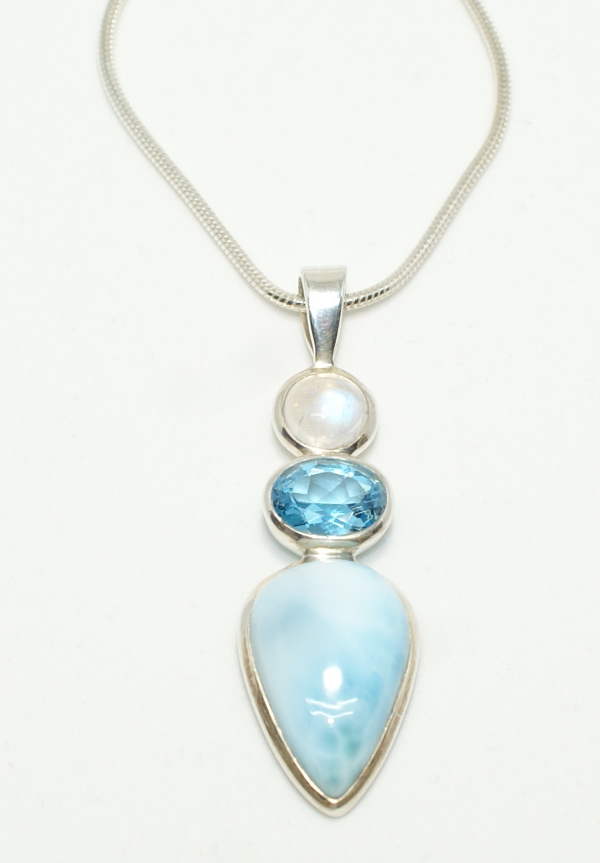 Silver in line pendant with round moonstone oval blue topaz and teardrop shaped larimar on snake chain.