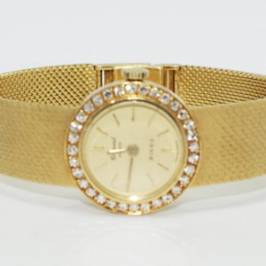 Ladies petitte yellow gold watch with round diamond bezel.