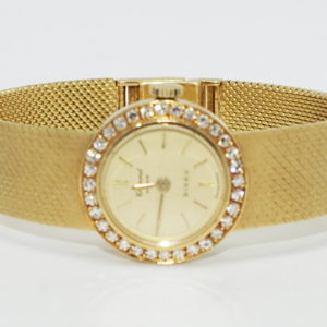 Ladies petitte yellow gold watch with round diamond bezel.
