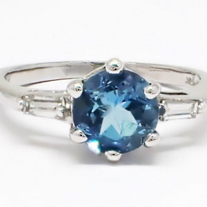White gold six claw set round aquamarine ring with baguette cut diamonds on the shoulders.