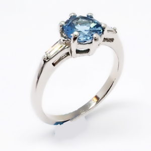 Side view of 10kt white gold six claw set round aquamarine and baguette diamond ring