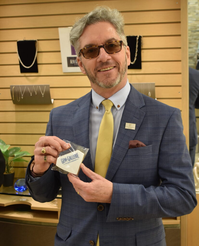 Mayor of Sherwood Park holding a cookie with the Gem Gallerie logo on it. 